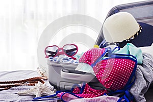 Pink bikini and clothes in suitcase on the bed