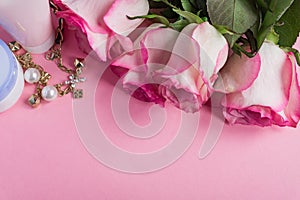 Pink blooming roses and face cream on pastel pink background. Romantic skincare floral frame. Copy space