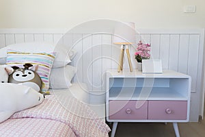 Pink and blue blanket with creative pillows on bed in colorful kids room