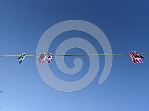 Pink and blue clothes pegs hanging on a yellow washing line in the sky photo