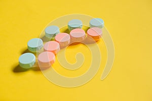Pink and blue contact lens cases on yellow background with empty copy space