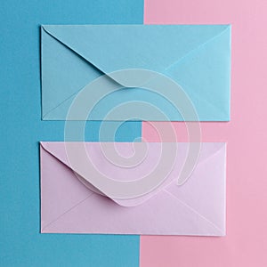 Pink and blue envelopes on colored pink and blue background. Top view.