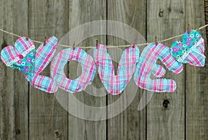 Pink and blue LOVE text and hearts hanging on clothesline by shabby wood fence