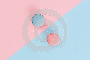 Pink and blue macarons on diagonally divided background.