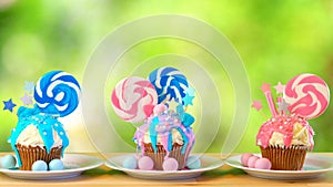 Pink and blue novelty cupcakes decorated with lollipop against garden background photo