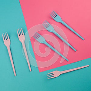 Pink and blue painted forks on the same colors background.