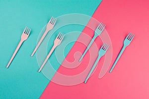 Pink and blue painted forks on the same colors background.
