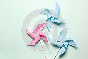 Pink blue paper spinners on light background. Kids toys colorful pinwheels on celebration party background. Top view, flat lay