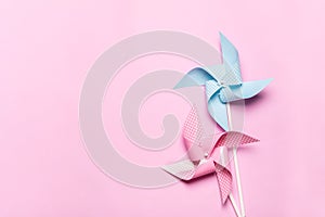 Pink blue paper spinners on light pink background. Kids toys colorful pinwheels on celebration party background. Top view, flat