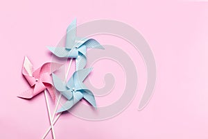 Pink blue paper spinners on light pink background. Kids toys colorful pinwheels on celebration party background. Top