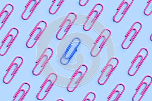 Pink and blue paperclip stand out from the crowd. One different concept. Male and female gender symbol. Feminism and unequal sexes