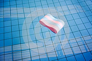 Pink and blue Pull buoy floating abandoned in swimming pool lone