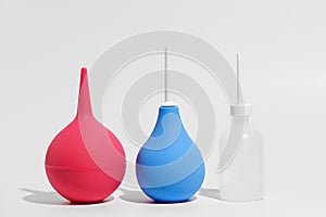 Pink, blue and white transparent enema on gray isolated background. The concept of medical drugs, pharmaceutical products, body