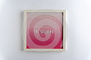 Pink Board Words That Spell Te Quiero (translation: I love you), on white background, horizontal photo