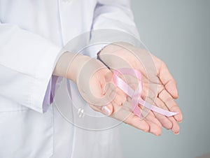 Pink bow in female doctorâ€™s hand with with background copy-space.