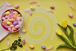 Pink bowl with colorful eggs, pink feathers, spring flowers. Happy Easter bright background. Post card with copy space