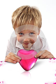 Pink box in a shape of heart with a child boy with a facial attitude ready to kiss someone