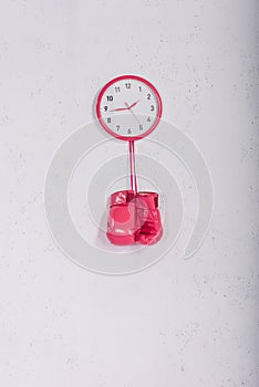 pink boxing gloves hanging at pink wall clock on white