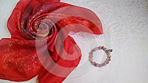 Pink bracelet made of natural pearls and pink quartz on a white background with a red rose made of silk fabric.