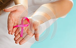 Pink breast cancer awareness ribbon on womans hands