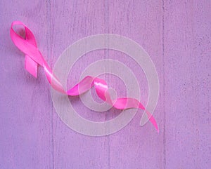 Pink breast cancer ribbon on white wooden table