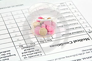 Pink and brown pills in graduated glass on medical questionnaire form