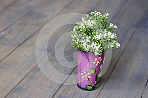 Pink bucket with florets. artificial green plant. wooden floor