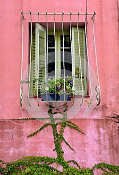 A pink building and window with green shutters