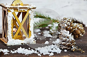 Pink burning candle with christmas decoration, fir tree, baubles and ribbon, in front of a white wooden wall or