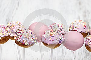 Pink cake pops on white wooden background