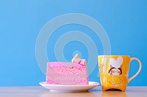 Pink cake and tea cup on blue background,select focus.