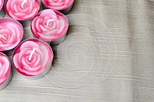 Pink candles are large in the left corner of the screen in the form of roses to the day of St. Valentine on a background of beige