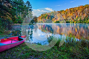 Pink canoe by colorful lake surrounded by fall colors in Smokey Mountains