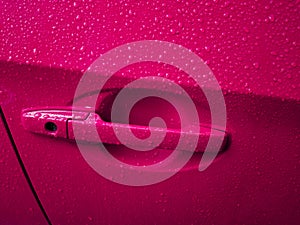 Pink car door handle with rain drops