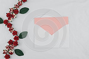 Pink card in white envelop decorate with red rose paper flowers