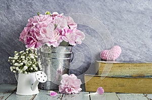 Pink carnation flowers in zinc bucket and book