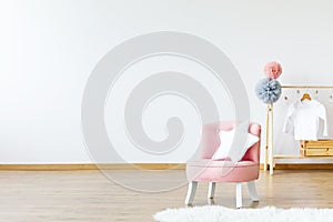 Pink chair with star shaped cushion standing in bright baby room