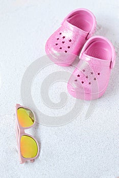 Pink child shoes and sunglasses on the beach, vacation vibe