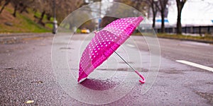 Pink children's umbrella on the wet asphalt