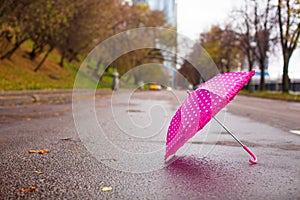 Pink children's umbrella on the wet asphalt