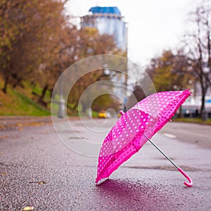 Pink children's umbrella on the wet asphalt