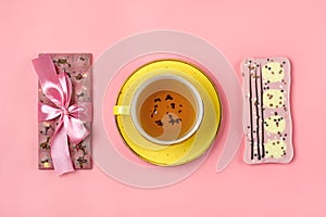 pink chocolate with raisins and nuts, yellow cup of black tea on pink background Dessert Time concept Flat lay Top view