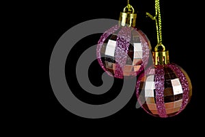 Pink Christmas baubles with glitters on black background