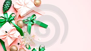 Pink Christmas card or New Year background, flat lay, copy space. Pastel pink gift boxes and green, golden decorations and