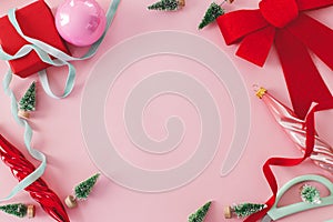 Pink Christmas. Modern Christmas flat lay with red bow, baubles, little green trees and ribbons on pink background. Creative