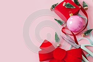 Pink Christmas. Modern Christmas red bow, baubles, little green trees and ribbons on pink background. Creative christmas