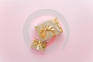 Pink Christmas or new year`s background, plain composition of golden Christmas gifts. Flatlay, empty space for greeting text.