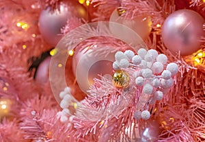 Pink Christmas tree with Christmas balls and white snow-covered berries.
