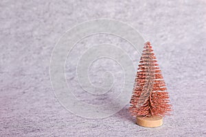 Pink Christmas tree on gray textile background. Minimal holiday concept. New year simple composition. Merry Christmas and happy