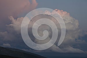 Pink cirro-cumulus and cumulus clouds in the evening light at sunset in the mountains photo